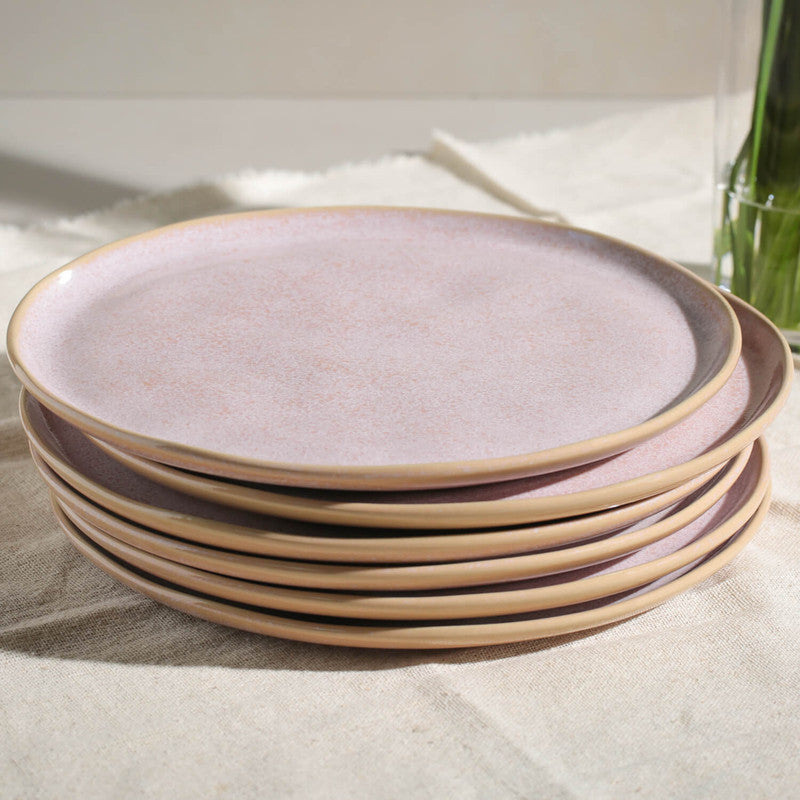Stack of pink ceramic plates on a light surface
