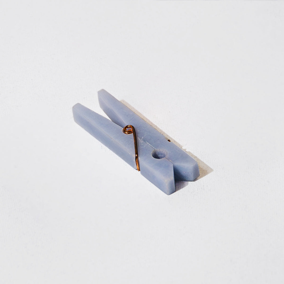 A light blue stone clothespin on a light grey background