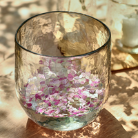 Clear glass with pink and white confetti on a wooden surface