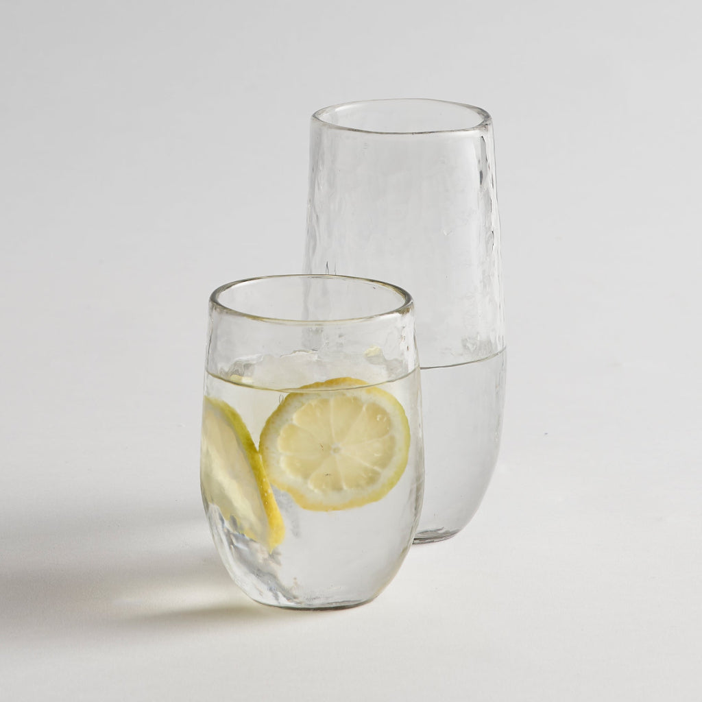 tall and medium pebbled drinking glasses with lemon water on a white background