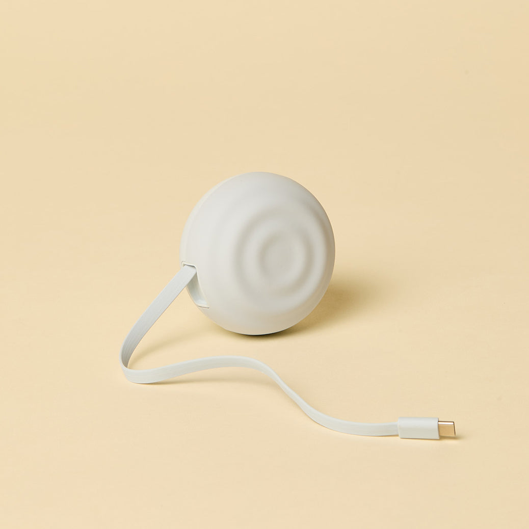 Retractable white charging cable on a beige background
