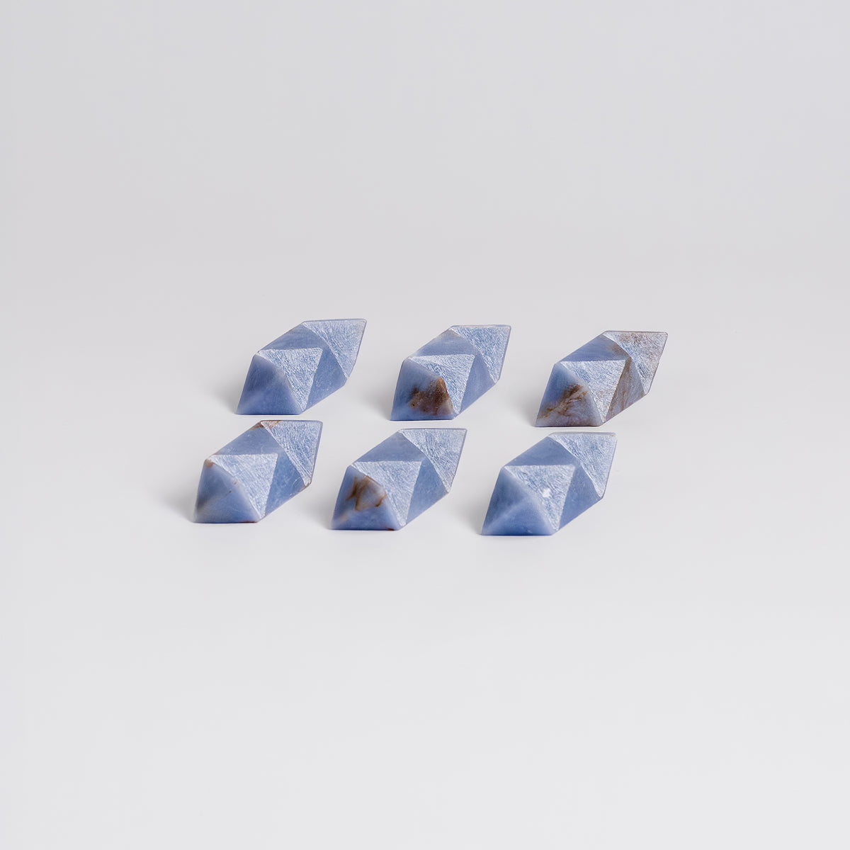 Set of six blue geometric stones on a light gray background
