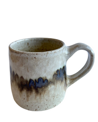 Ceramic mug with light and dark neutral glaze details on a white background