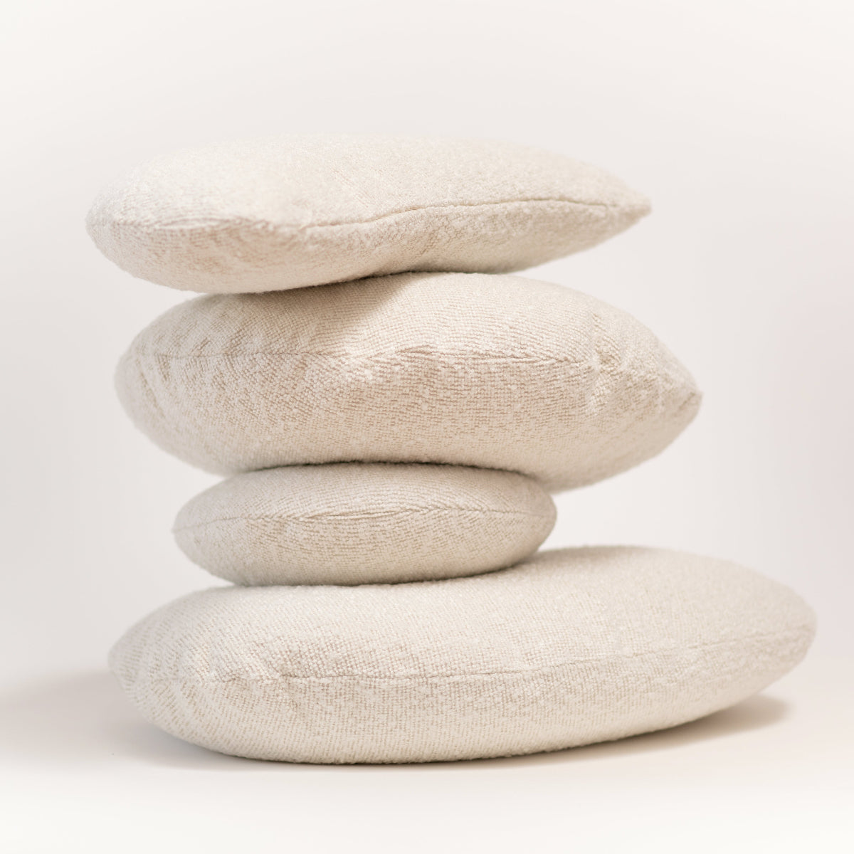 Stack of four beige pillows on a white background