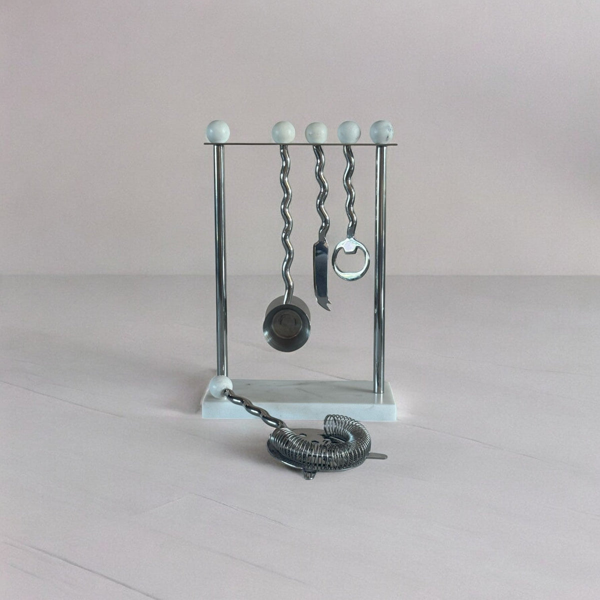 Metallic barware set with hanging tools on a light gray background