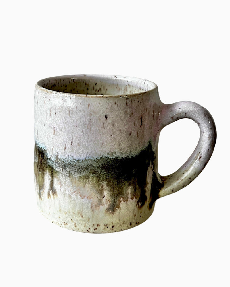 Ceramic mug with light and dark neutral glaze details on a white background