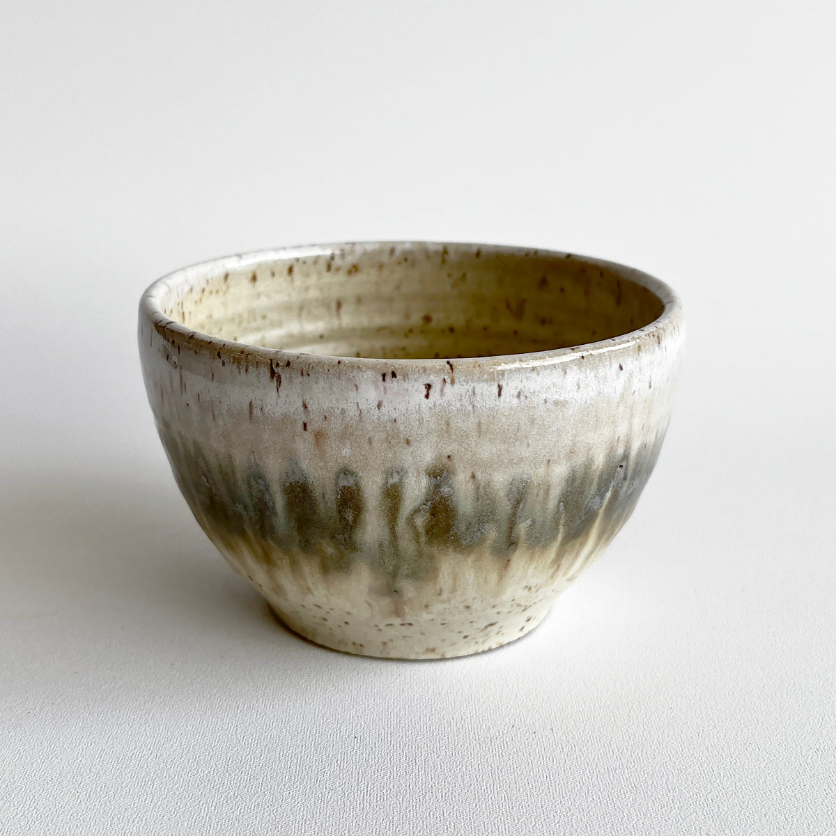 Ceramic bowl with light and dark neutral glaze details on a white background