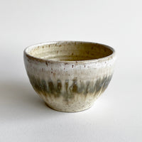Ceramic bowl with light and dark neutral glaze details on a white background