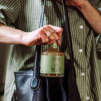 Person holding a bottle labeled 'Tiden' against a blurred background