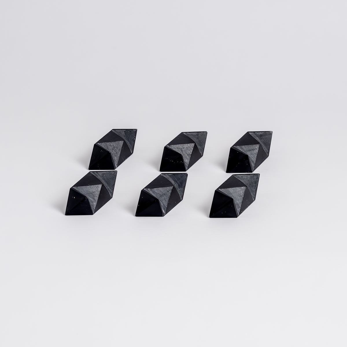 Six black geometric pyramid-shaped objects on a light gray background