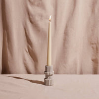 Candle in a textured holder against a beige curtain