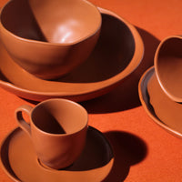 Terracotta ceramic tableware set on an orange background
