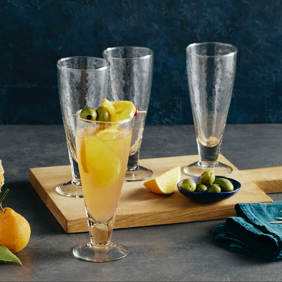 drink with olives and lemon slices in a glass on a wooden board with a dark background