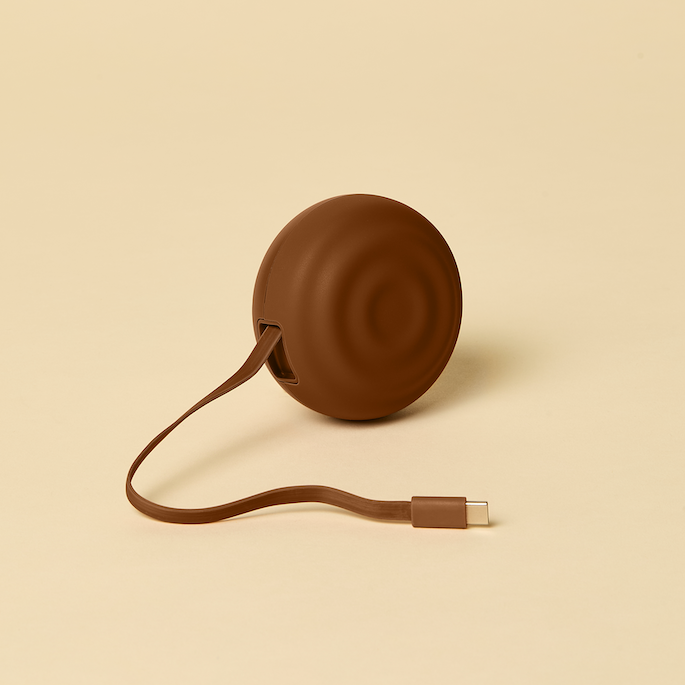 Brown circular device with a cable on a beige background