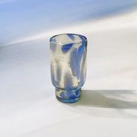 Clear drinking glass with blue accent on a white surface