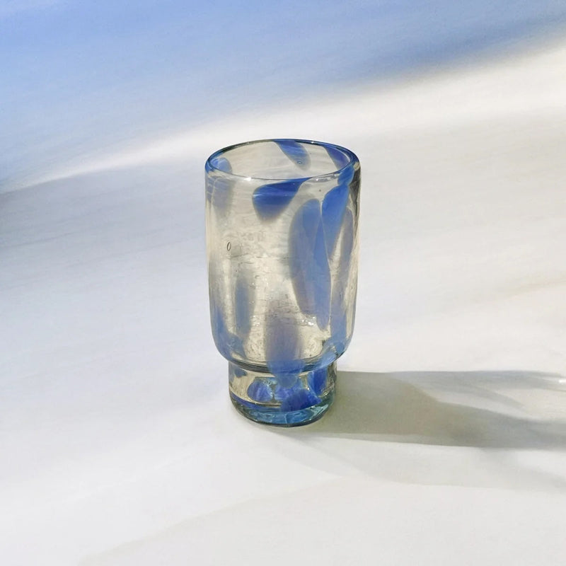 Clear drinking glass with blue accent on a white surface