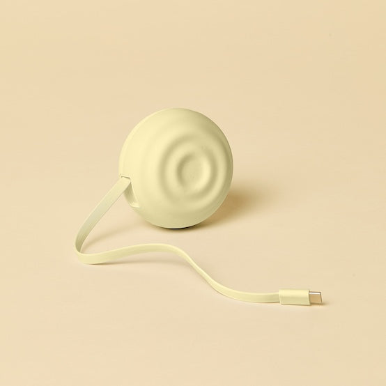 Light yellow electronic charging device with a cable on a beige background