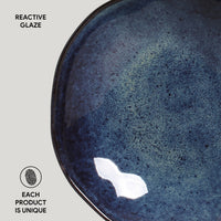 Blue ceramic bowl with reactive glaze on a white background