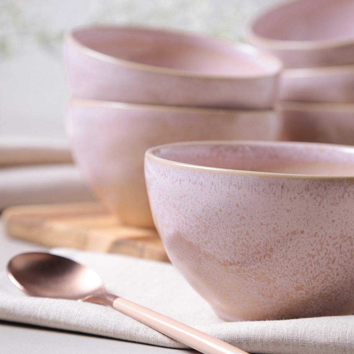 Set of pink ceramic bowls with a spoon on a light background