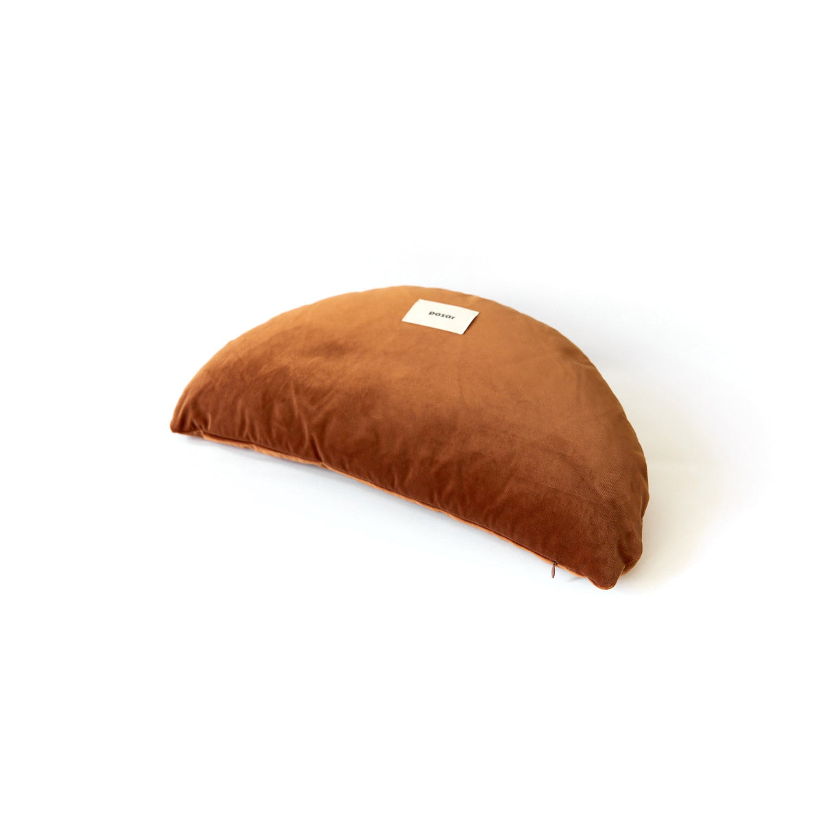 Brown crescent-shaped pillow with a label on a white background