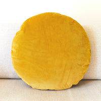 Round yellow cushion on a beige sofa