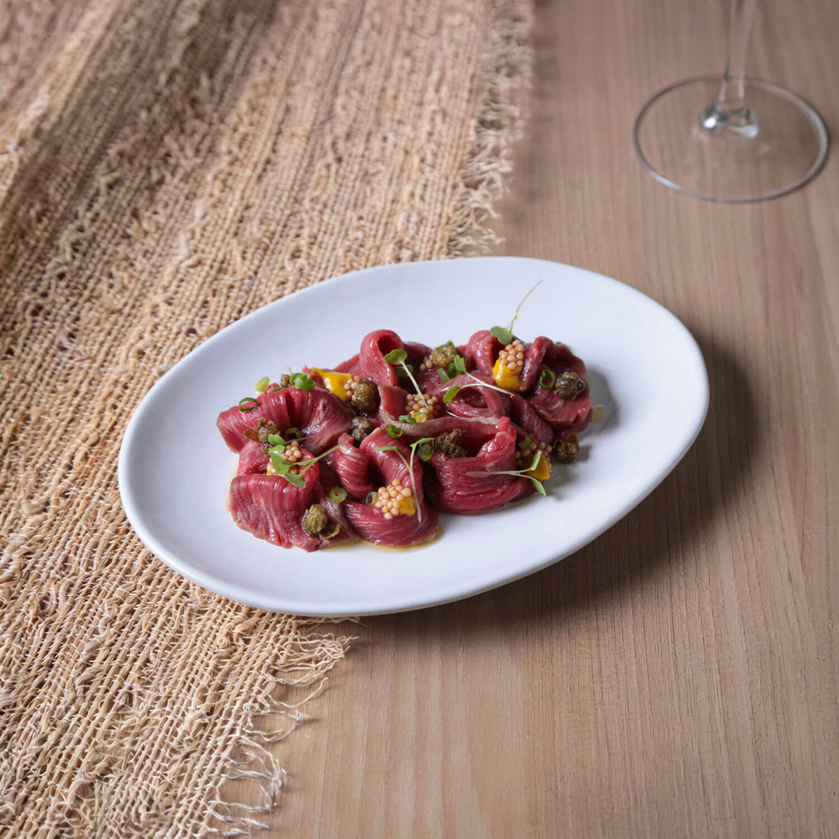 Plated dish of raw fish with garnishes on a wooden table