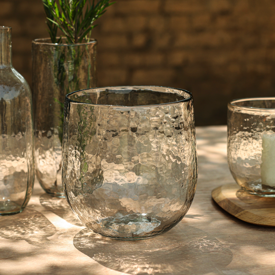 Clear glass vessels on a wooden surface with a blurred natural background
