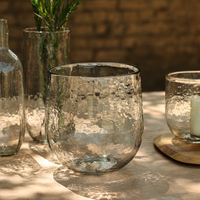 Clear glass vessels on a wooden surface with a blurred natural background