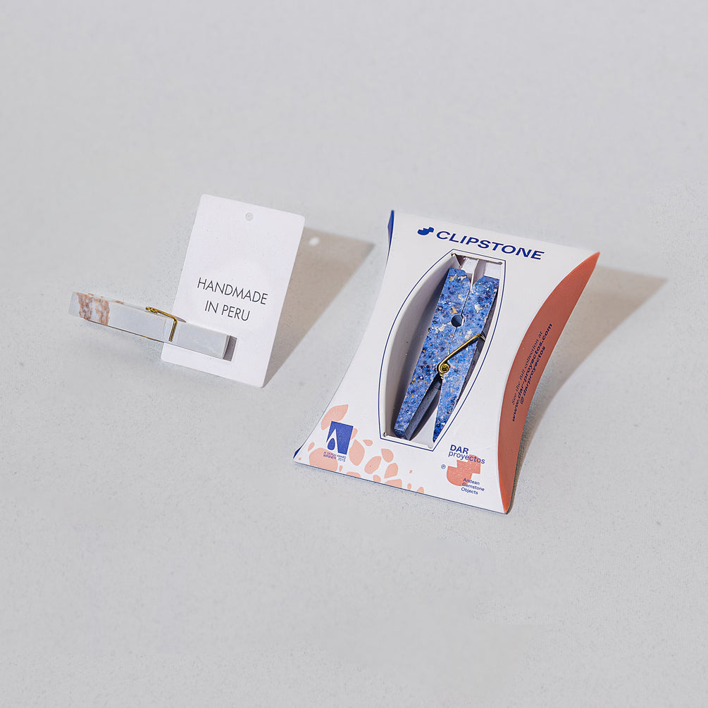 a blue stone clothespin in packaging next to a notecard that says 'Handmade in Peru'