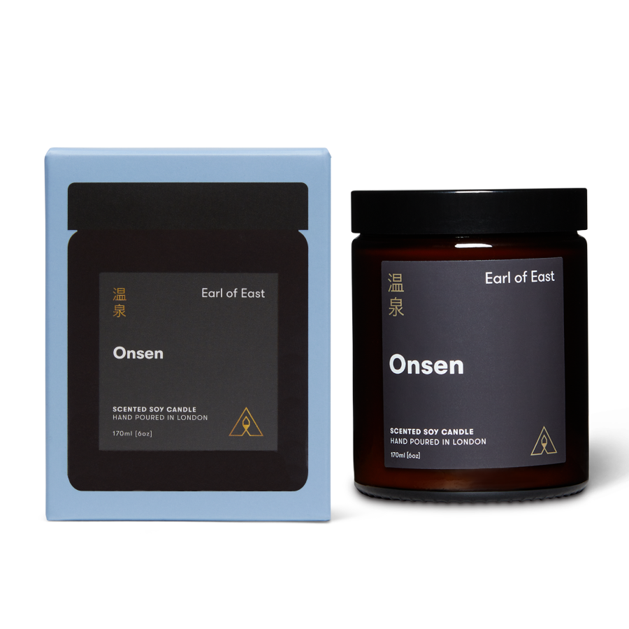 Scented soy candle in a lidded glass jar with a branded label next to a branded box both reading Earl of East Onsen