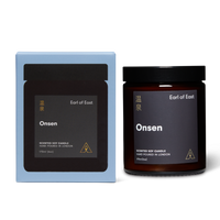 Scented soy candle in a lidded glass jar with a branded label next to a branded box both reading Earl of East Onsen