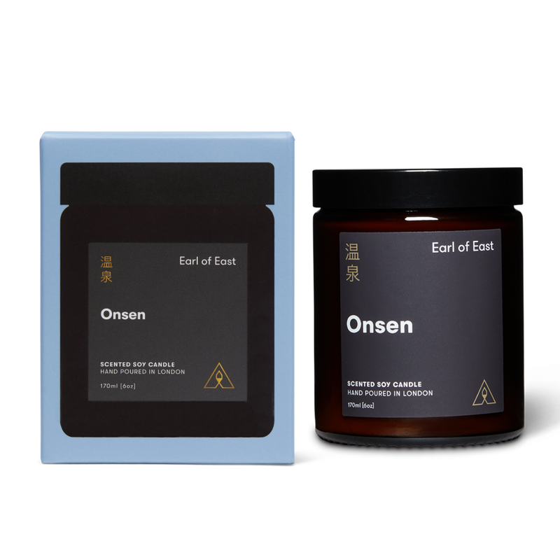 Scented soy candle in a lidded glass jar with a branded label next to a branded box both reading Earl of East Onsen