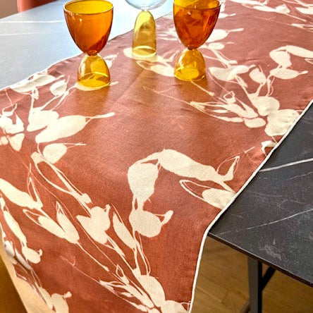 Table runner with floral pattern on a table with orange glasses.