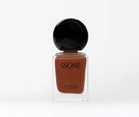 Amber nail polish bottle with black cap on a white background