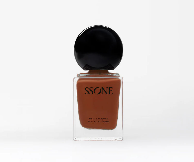 Amber nail polish bottle with black cap on a white background