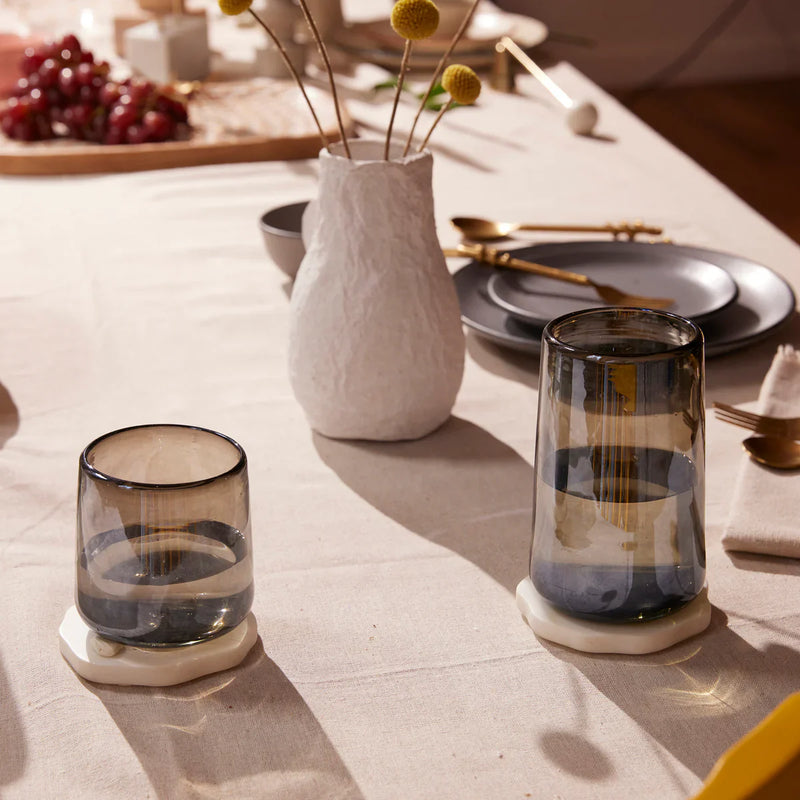 Table setting with glasses, vase, and plates on a light surface