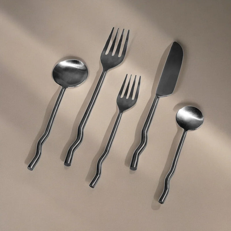 Set of silver cutlery including spoon, fork, and knife on a beige background