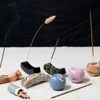 Incense sticks and ceramic incense holders on a white surface with a dark background