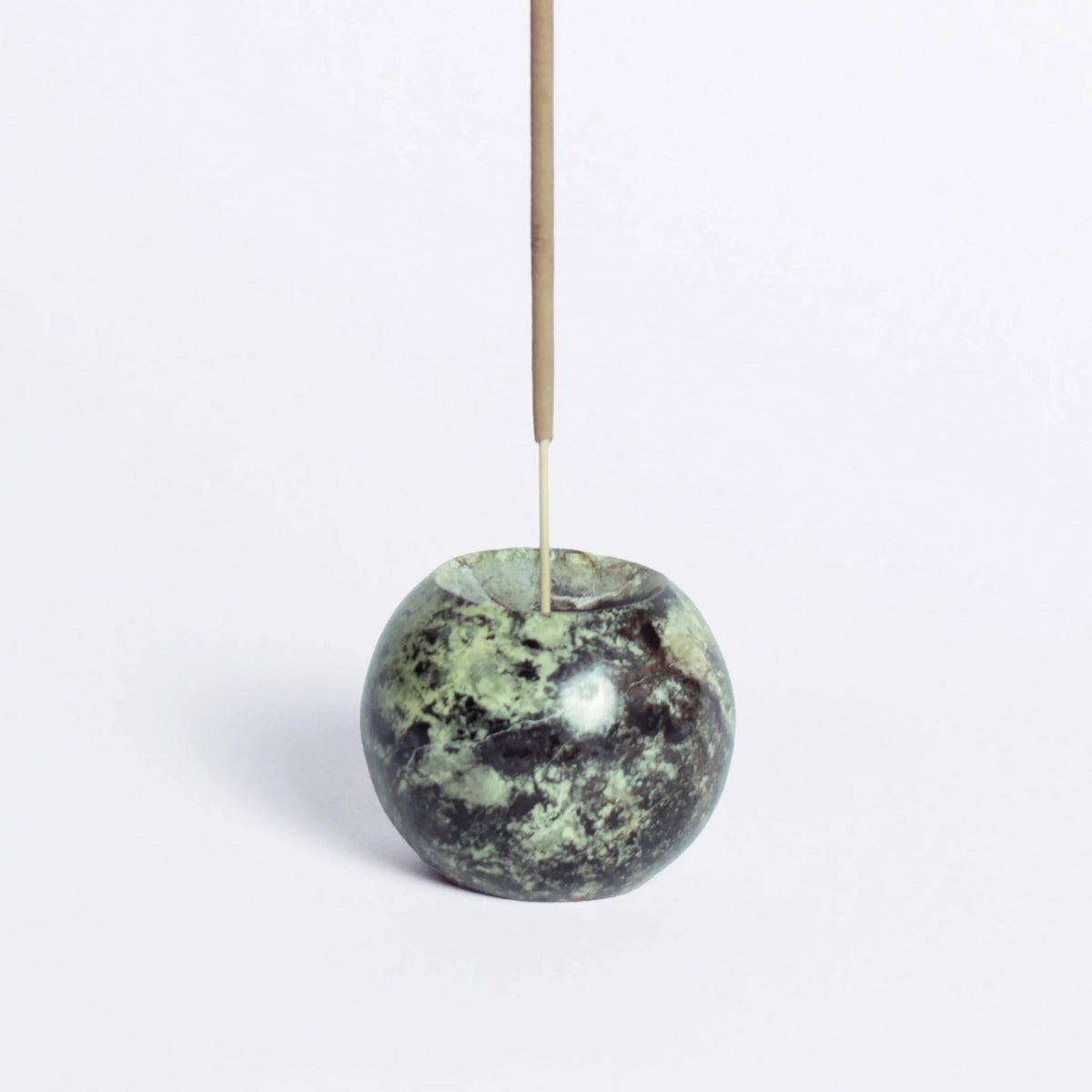 Green stone incense holder with a single incense stick on a white background