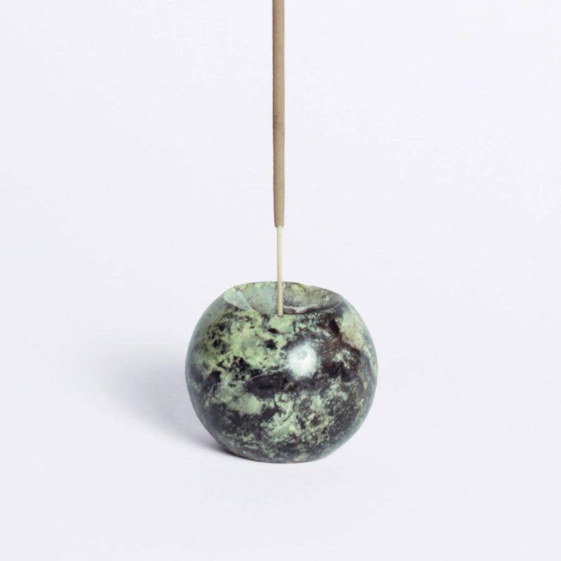 Green stone incense holder with a single incense stick on a white background