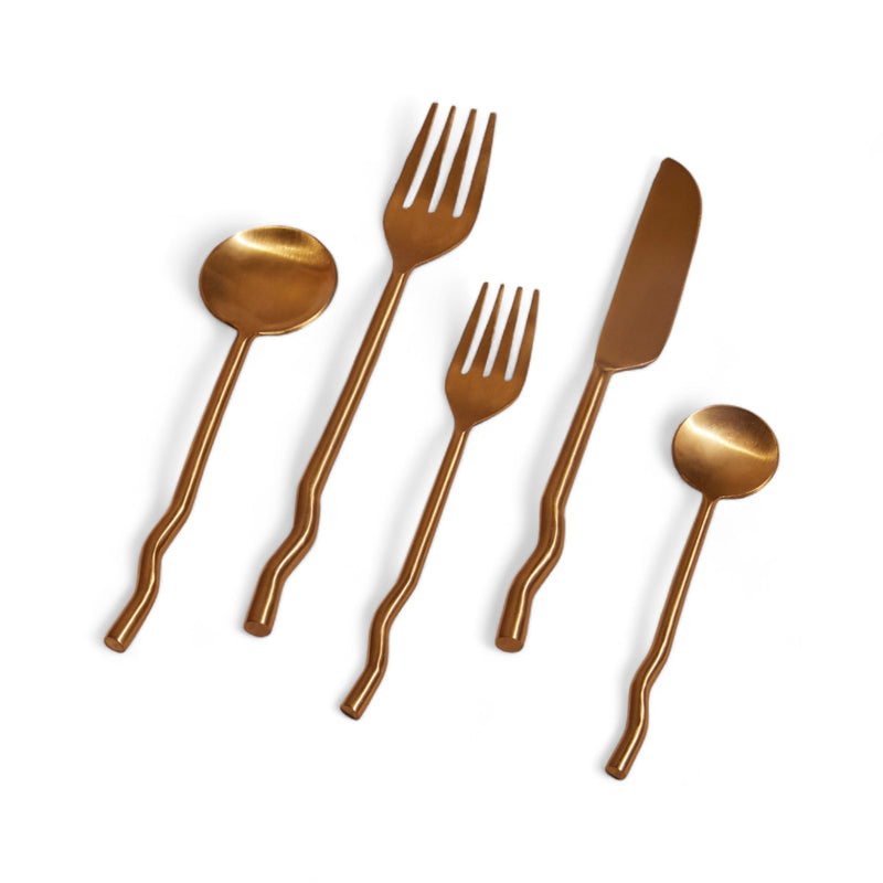 Set of brass cutlery including spoon, fork, and knife on a white background