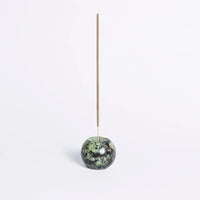 Incense stick holder with a green marbled stone on a white background