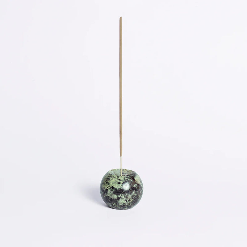 Incense stick holder with a green marbled stone on a white background