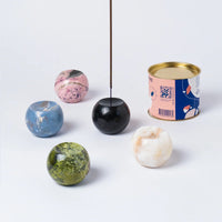 Colorful marbled incense holder spheres and a can on a white background