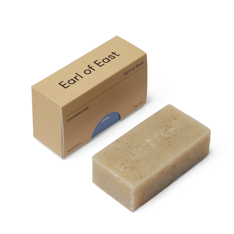 Beige cleansing bar of soap next to an 'Earl of East' branded cardboard box