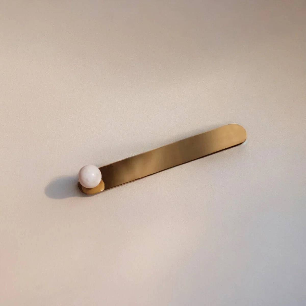 Brass bar with a white sphere incense holder on a beige background