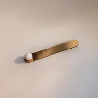 Brass bar with a white sphere incense holder on a beige background
