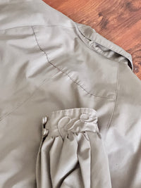 Close-up of taupe trench coat on a wooden surface background