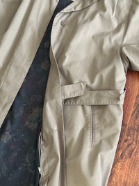 Taupe trench coat with visible inner lining on a wooden surface