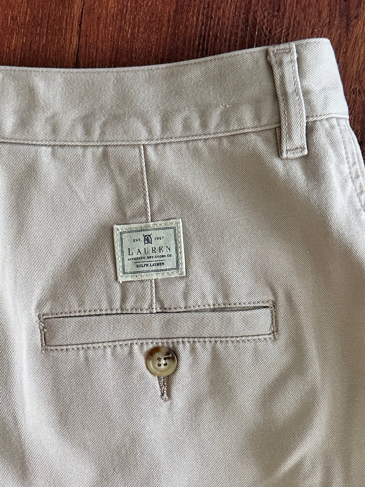 Close-up of a beige pants pocket with a Ralph Lauren label on a wooden surface